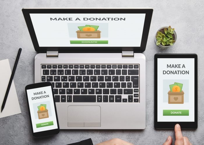 Donation concept on laptop, tablet and smartphone screen over gray table. Top view